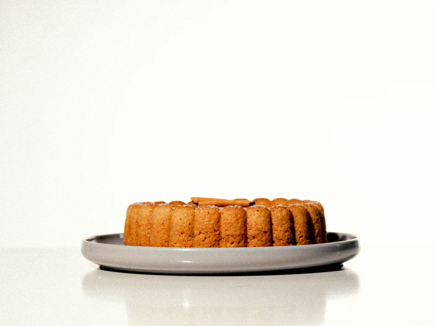 Pastel redondo sobre un plato gris en fondo blanco.