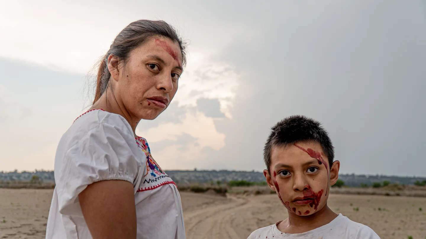 Retrato de una mujer y un niño con el rostro marcado, mirando a cámara.