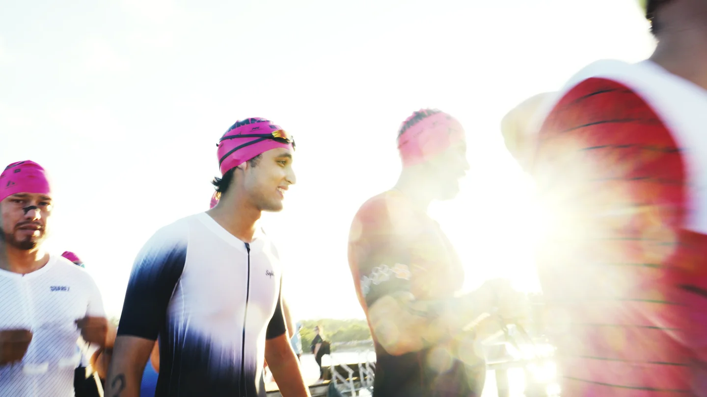 Hombres con gorros de natación rosas a contraluz.