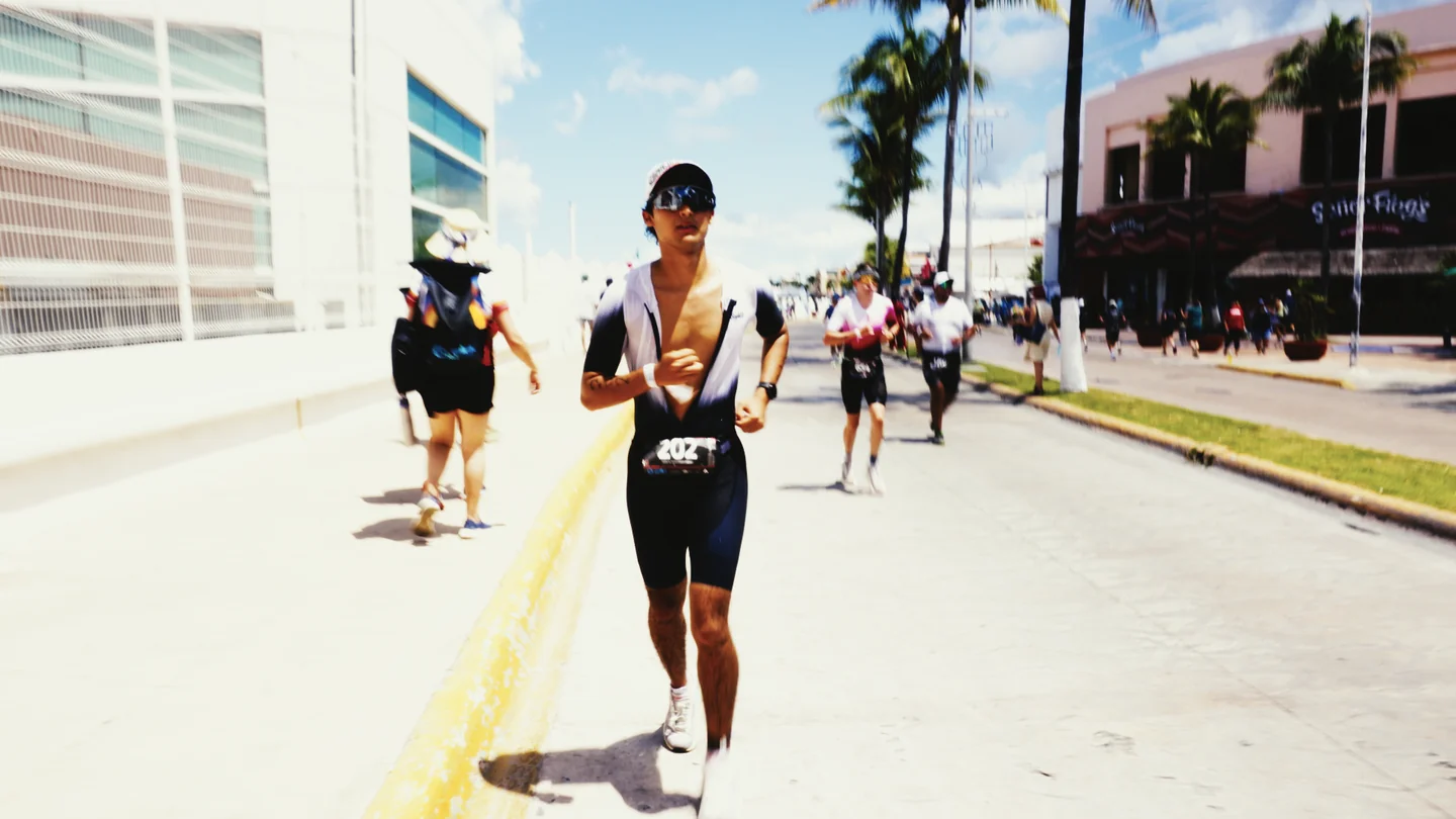 Hombre corre por una calle soleada junto a otros participantes.